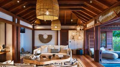 Elegant St. Barth villa living area featuring refined Balinese woodwork, wicker lighting, and a live-edge wood coffee table.