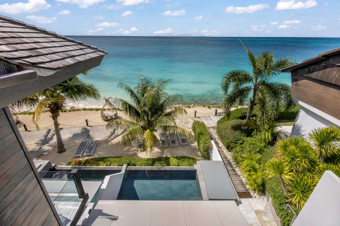 Breathtaking ocean views from Villa Colibri Dance featuring a private infinity pool, sandy beach area, and turquoise waters.