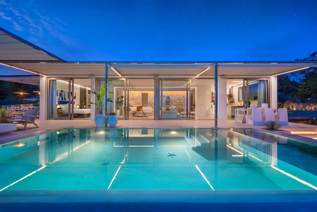 Illuminated luxury villa Cuca at night, featuring a saltwater infinity pool and seamless indoor-outdoor living spaces.