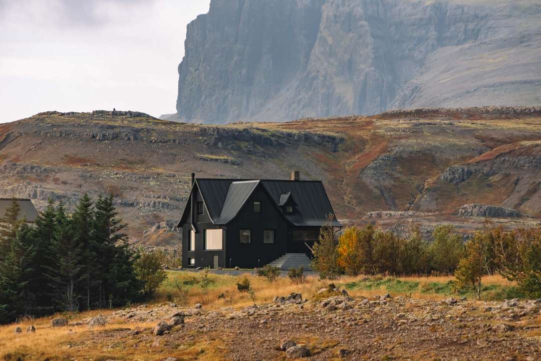Black corrugated iron farmhouse at Dalur Luxury Resort, surrounded by rugged mountains and scenic autumn landscapes.
