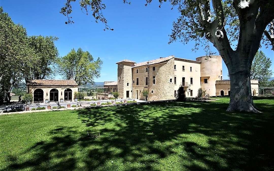 Historic stone manor at Demeure De Bonnieux, featuring sprawling lawns and mature trees in the scenic Luberon countryside.