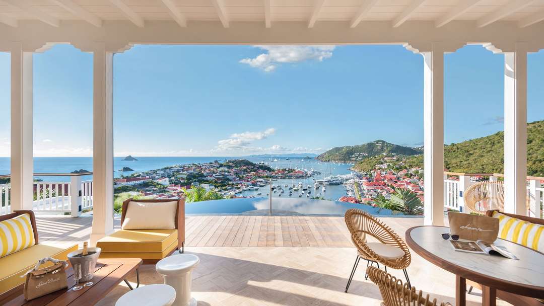Expansive outdoor terrace at Villa Diane featuring a shaded lounge, infinity pool, and breathtaking views of Gustavia harbor.