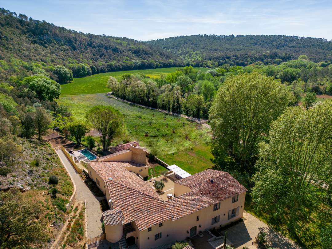 Aerial view of Domaine Royal, a historic stone bastide with terracotta roof, nestled in lush Var countryside and vineyards.