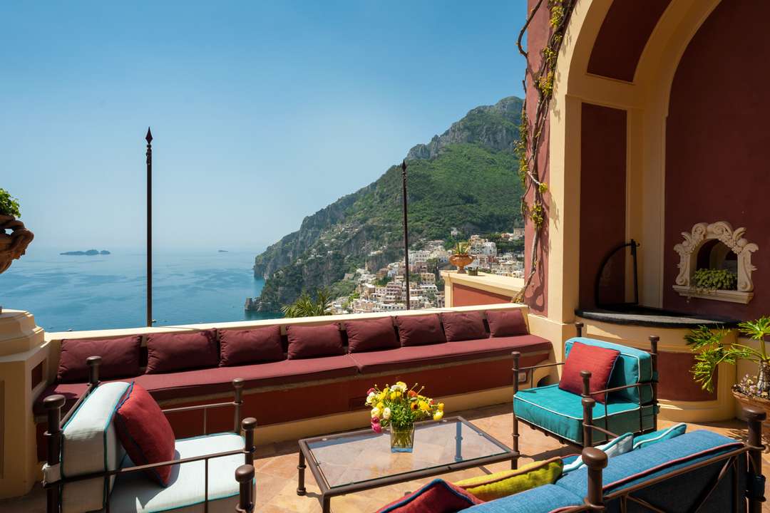 Panoramic sea and Positano village views from Villa Dorata's elegant outdoor terrace with comfortable lounge seating.