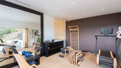 Fully equipped, air-conditioned fitness room featuring state-of-the-art wooden exercise equipment and a large mirrored wall.