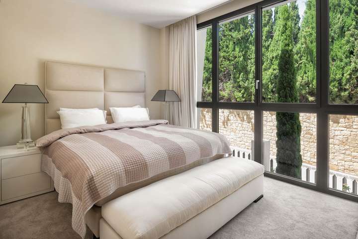 Elegant guest bedroom at El Chambao Penthouse featuring a plush king-size bed and large windows with serene mountain views.