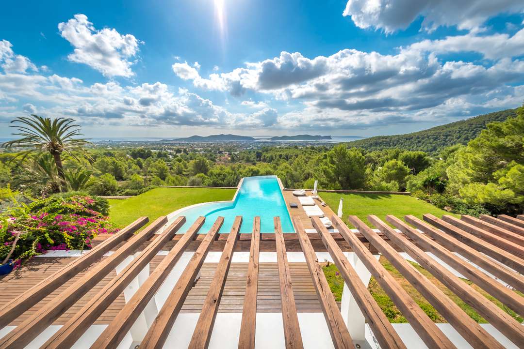View from a sleek wooden pergola terrace overlooking the stunning infinity pool and expansive sea views towards Las Salinas.
