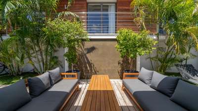 Secluded wooden outdoor lounge in Villa Etj, St. Barths, featuring chic grey sofas surrounded by lush tropical foliage.