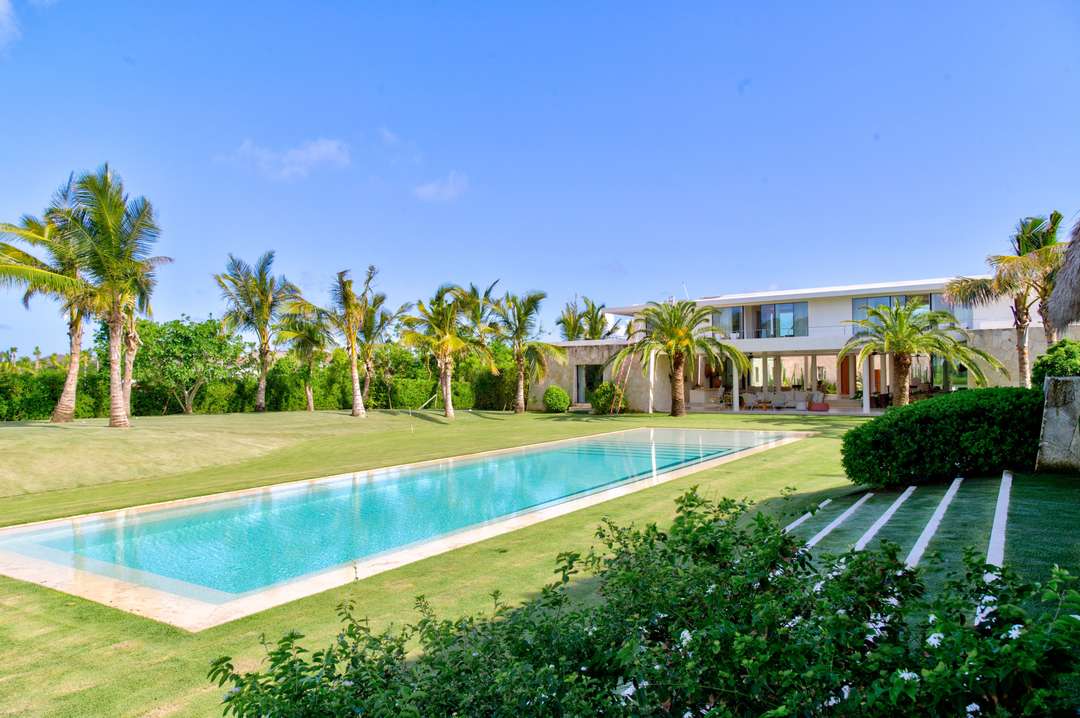 Forte Taino's modern exterior features a stunning private pool, manicured lawns, and palm trees in exclusive Punta Cana.