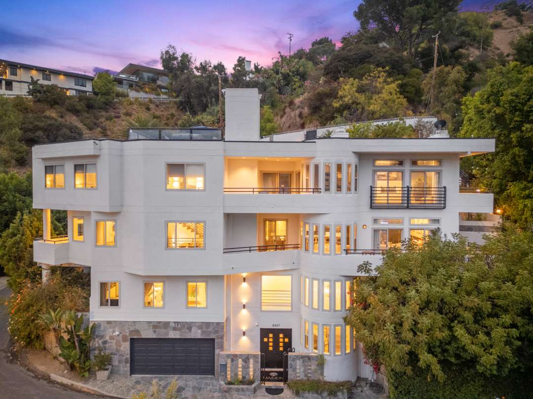 Elegant multi-story Hollywood Hills villa above Sunset Strip featuring a modern white facade and expansive windows at dusk.