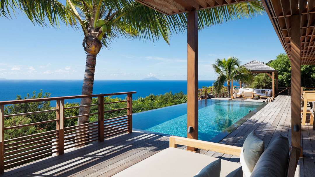 Expansive wooden terrace and heated infinity pool offering panoramic ocean views at the luxury Villa Gypsea in St. Barths.