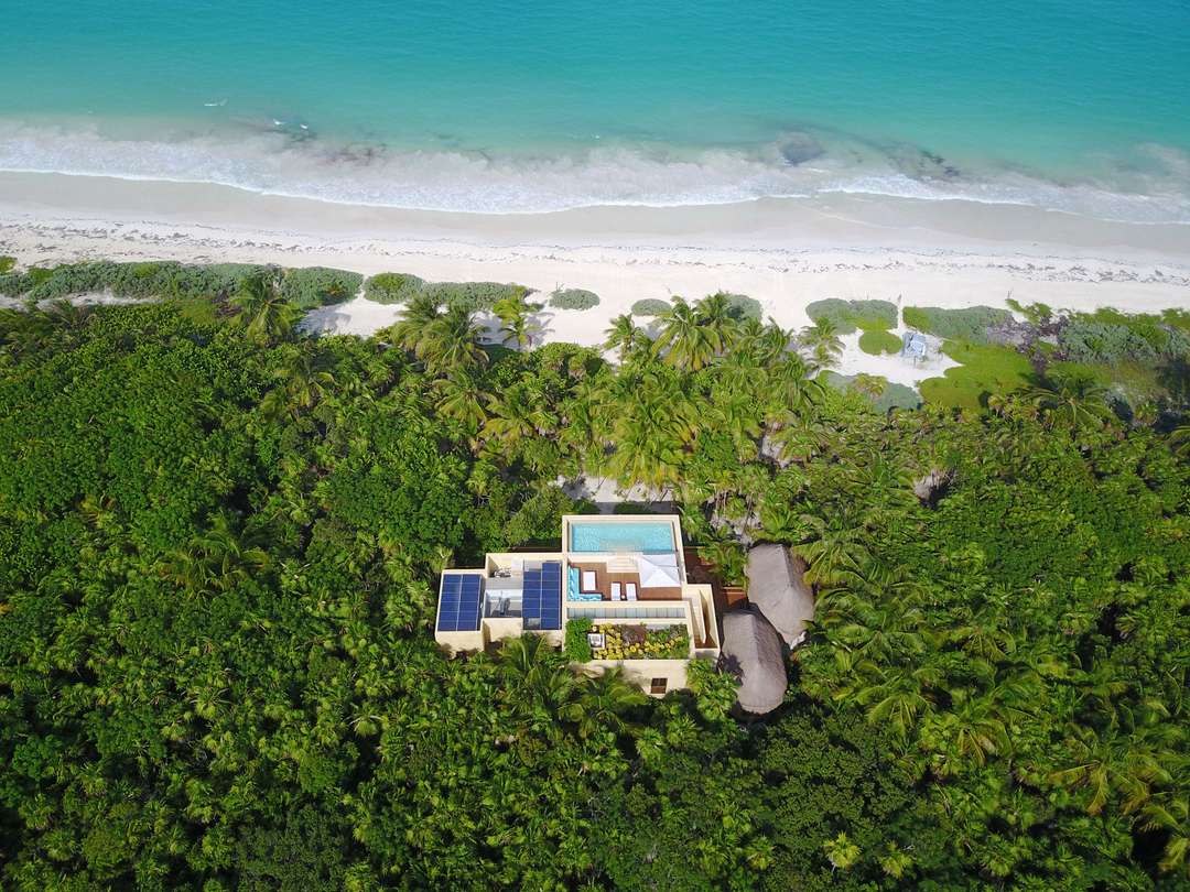 Aerial view of Hacienda Chekul, a luxury beachfront villa in Tulum surrounded by lush jungle, featuring a rooftop pool.