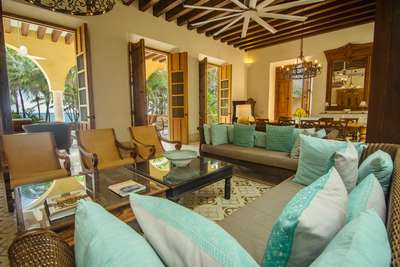 Spacious luxury living area with wooden ceiling beams, elegant seating, and open doors leading to the tropical terrace.