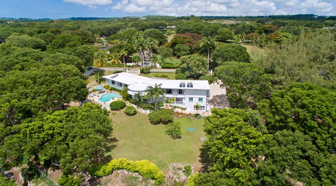 Aerial view of luxury Halle Rose villa in Sandy Lane, Barbados, showcasing a private pool, lush gardens, and distant sea views.