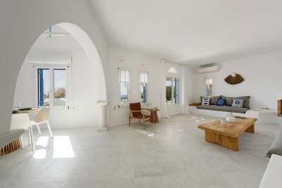 Minimalist open-plan living and dining space in a luxury Golden Beach villa, featuring whitewashed arches and natural light.