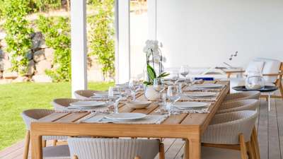 Elegant covered outdoor dining area seating eight, featuring a wooden table and woven chairs at Villa Indigo St-Barths.