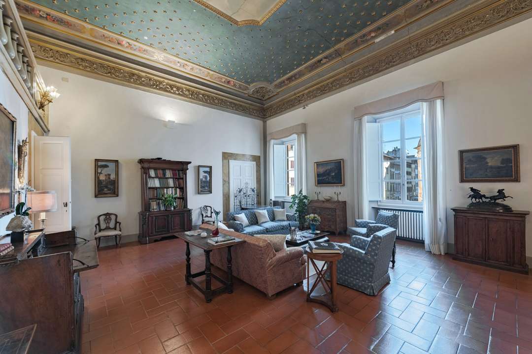 Elegant living room in a Florentine palazzo with terracotta floors, antique wood furnishings, and a star-frescoed ceiling.
