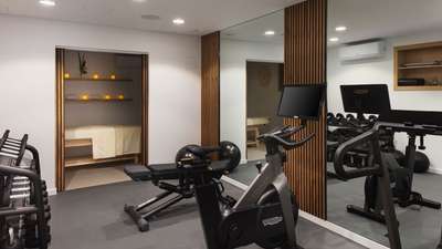 Private fitness room at Villa Jnana equipped with a Technogym bike, free weights, and an elegant adjacent massage room.