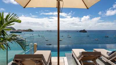 Shaded sun loungers in the magnificent infinity pool at Villa June, overlooking the azure Caribbean Sea and tranquil bay.