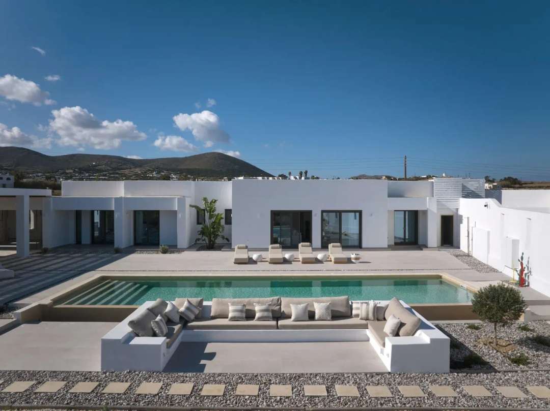 Contemporary Cycladic villa Kaiki White in Paros, featuring a pristine private pool, sunken lounge, and clean white lines.