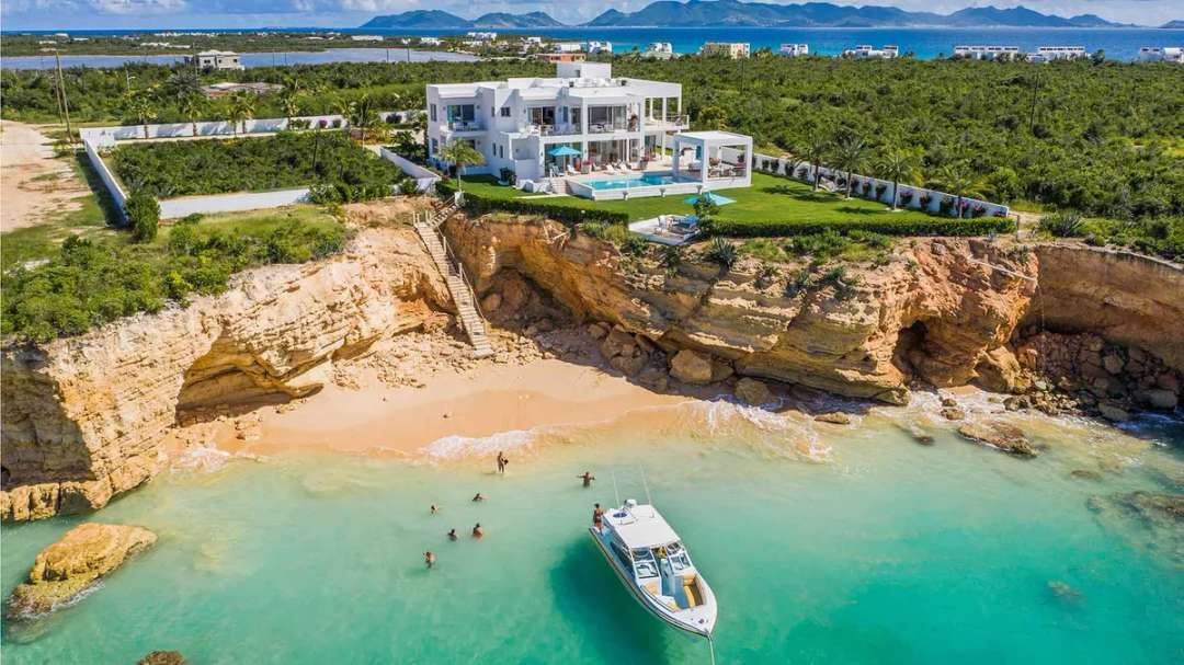 Aerial view of Kandara villa in Anguilla, a modern white estate on a cliff with stairs to a private beach and turquoise sea.