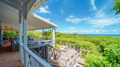 Expansive covered outdoor terrace featuring comfortable lounge seating, natural wood details, and panoramic ocean views.