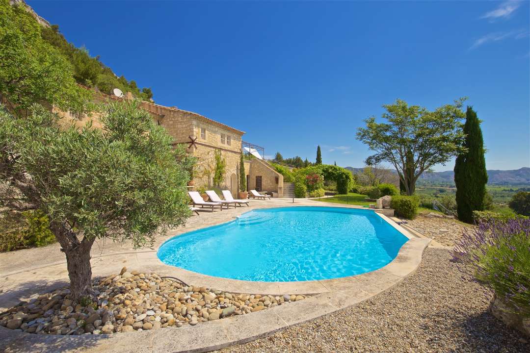 Freeform pool at luxury villa La Citadelle in Les Baux, featuring stone architecture and panoramic countryside views.