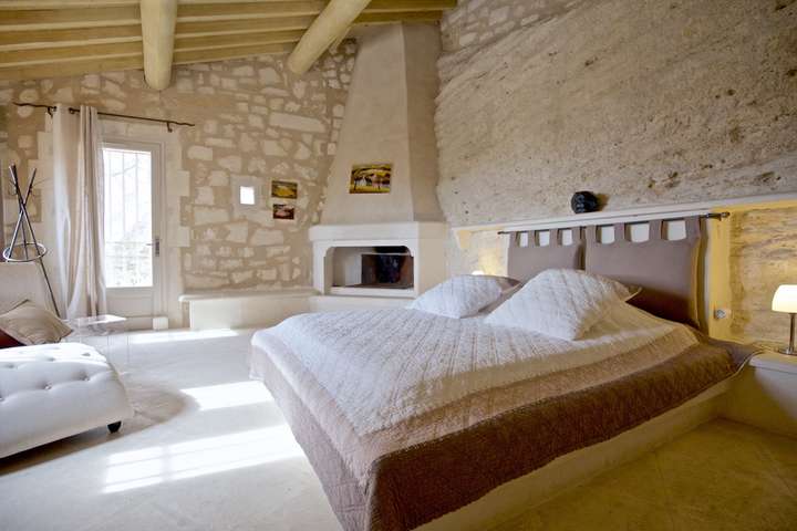 Serene bedroom at La Citadelle featuring a queen bed, exposed beams, and natural stone walls for a peaceful luxury retreat.
