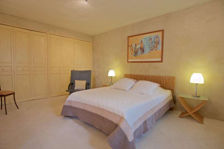 Serene bedroom offering a comfortable queen bed, warm wooden accents, and spacious built-in closets for a peaceful stay.