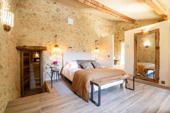 Luxurious air-conditioned bedroom with exposed stone walls, comfortable bed, and elegant rustic decor in Rustrel.