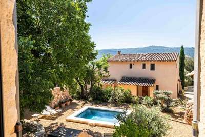 Stunning window view of the private swimming pool, courtyard garden, and scenic Luberon countryside at La Petite Ocrière.