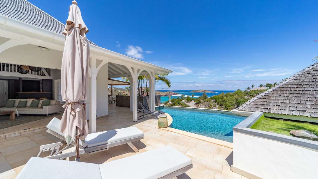 Elegant private pool and sun loungers on a light-tiled terrace at Villa Lagon Jaune, offering breathtaking ocean views.