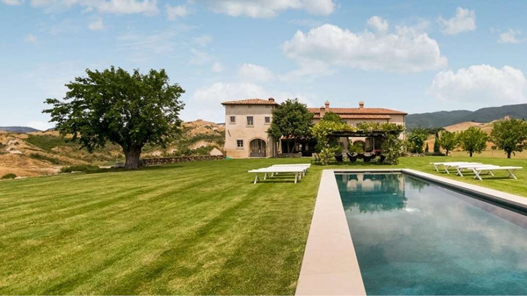 Classic Tuscan villa Le Caselle with a large heated pool, manicured lawn, and scenic countryside views in Siena.