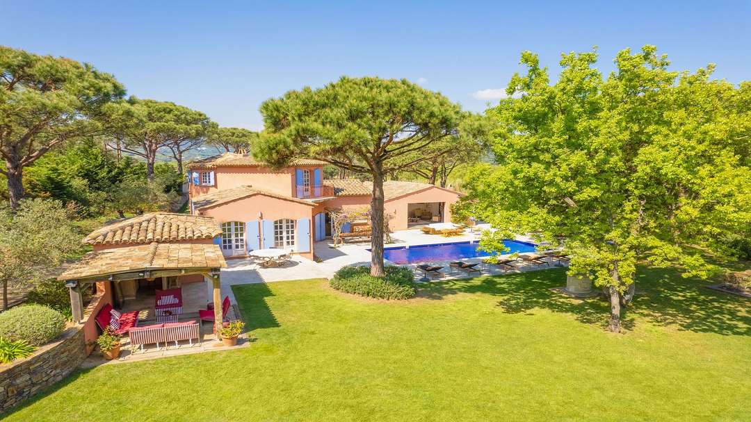 Aerial view of Le Cigalou in Ramatuelle, featuring a large private pool, lush gardens, and elegant outdoor living spaces.