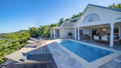 Elegant covered terrace with alfresco dining and a private pool at Villa Les Acajous, boasting stunning Caribbean views.