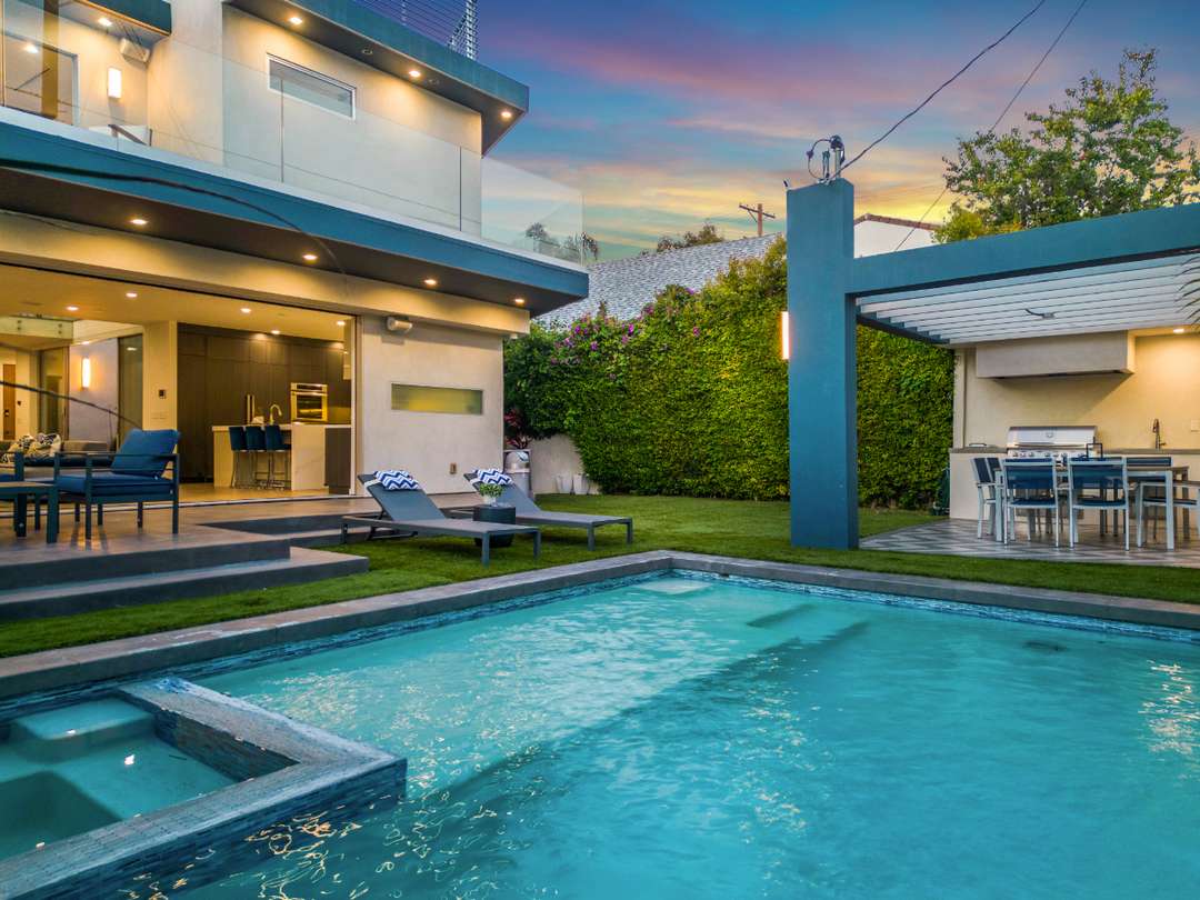 Luxury West Hollywood villa exterior featuring a private heated pool, loungers, and a modern outdoor kitchen.