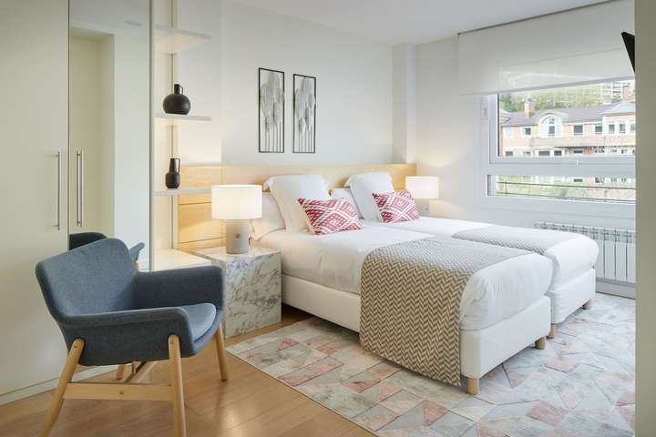 Chic en-suite bedroom featuring twin beds, a luxurious marble nightstand, and elegant decor in this San Sebastián villa.