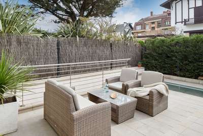 Private outdoor terrace in San Sebastian villa featuring comfortable wicker seating, a glass table, and peaceful surroundings.
