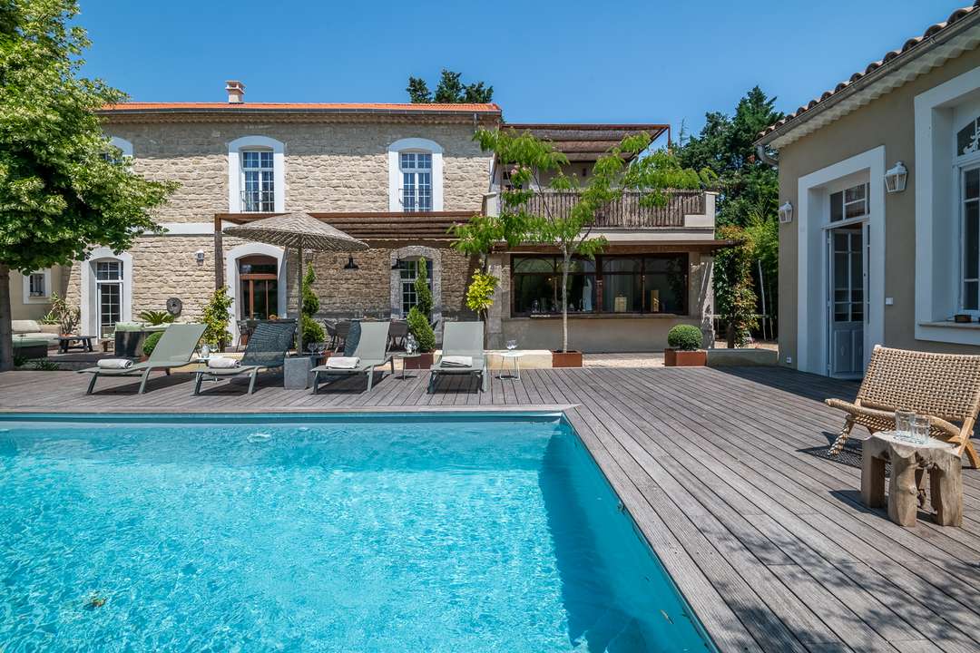 Private pool and wooden sun deck at Maison les Nomades, a luxury stone villa in L’Isle-sur-la-Sorgue with modern amenities.