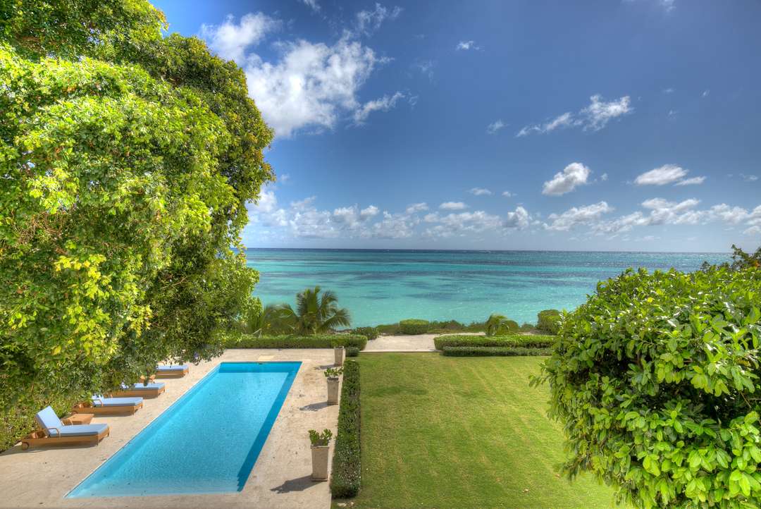 Elevated view of the private pool, expansive lawn, and stunning turquoise ocean views from this luxury villa.