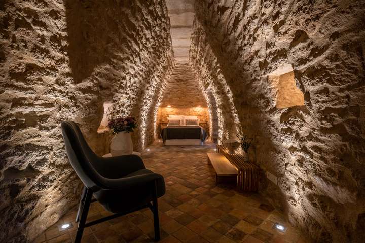 Unique luxury bedroom in a historic stone cave with dramatic lighting, terracotta tiles, and contemporary touches.