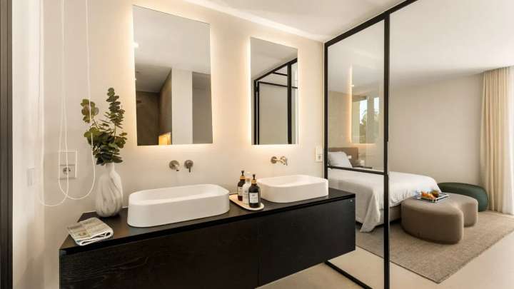 Modern bedroom suite at Monteros Sands featuring a glass-partitioned en-suite bathroom with dual sinks and floating vanity.
