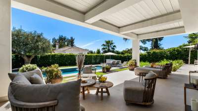 Luxurious covered terrace with plush seating at Monteros Sands, offering serene views of the private pool and olive trees.