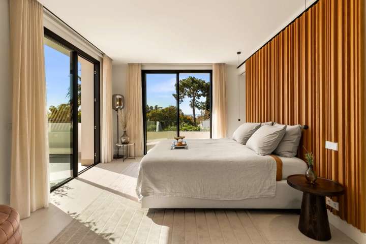 Luxury bedroom suite at Monteros Sands featuring a wood slat wall, plush bed, and private terrace with stunning sea views.