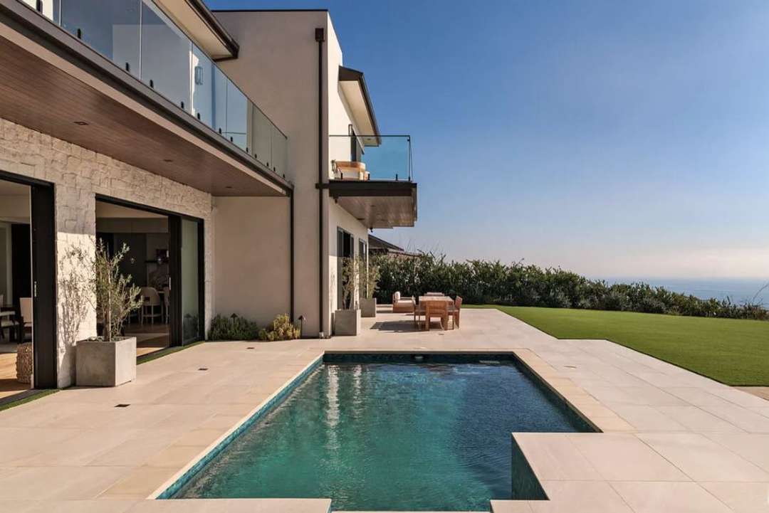 Contemporary coastal estate in Malibu featuring a private pool, stone patio, and sweeping panoramic ocean views.
