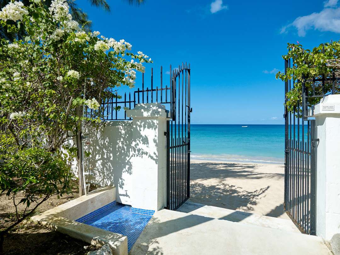 Wrought-iron gates open from New Mansion's lush gardens directly onto the pristine white sands of Paynes Bay Beach.