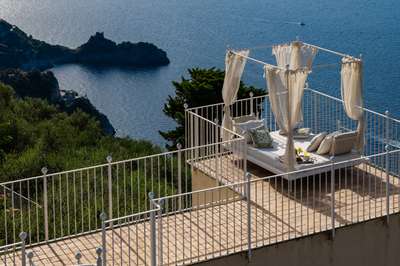 Romantic four-poster daybed on a private terrace at Villa Nume, offering breathtaking panoramic views of the turquoise sea.