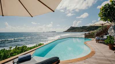 Luxurious poolside relaxation at Villa Nureyev, featuring a wooden deck, elegant loungers, and breathtaking ocean vistas.