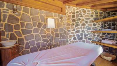 Dedicated massage room offering a luxurious retreat with rustic stone walls, warm lighting, and a soothing atmosphere.