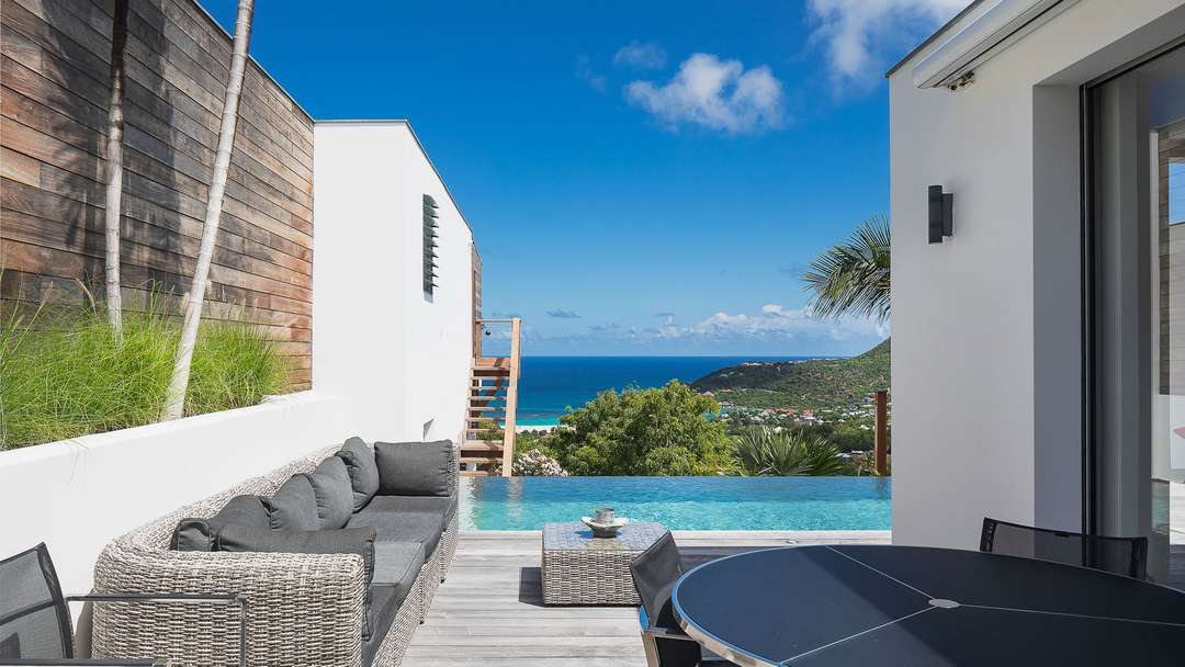 Elegant outdoor dining and lounge area on the exotic wood terrace by the heated infinity pool, offering sweeping ocean views.